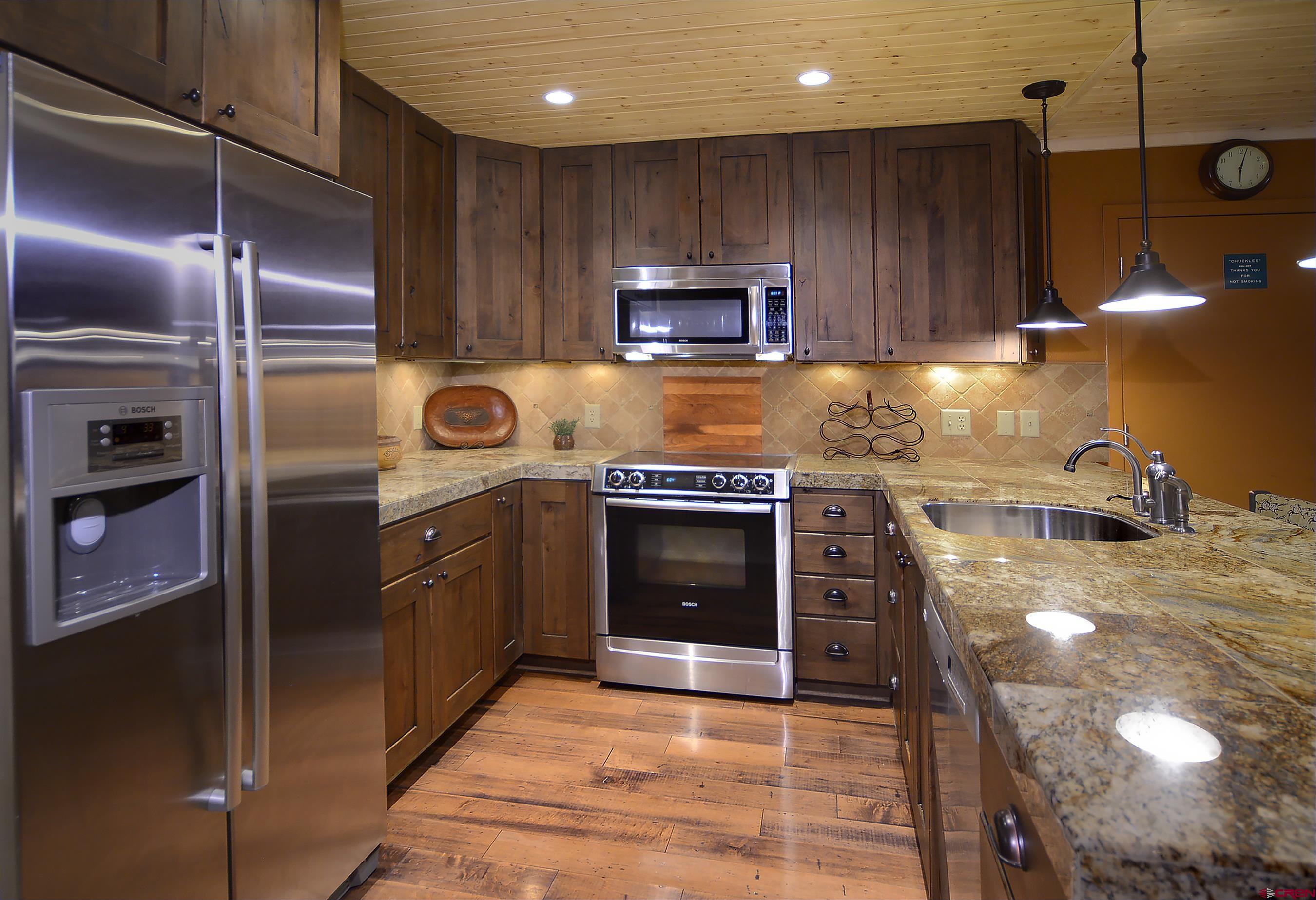 35 Emmons Road, Unit 3 Crested Butte, CO 81225 - Photo 13 of 25 a kitchen with kitchen island granite countertop wooden cabinets and a stove