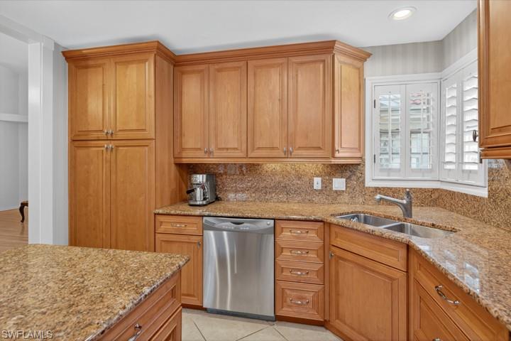43 Grey Wing Point Naples, FL 34113 - Photo 26 of 50 Kitchen with dishwasher, light stone counters, tasteful backsplash, light tile patterned floors, and brown cabinets