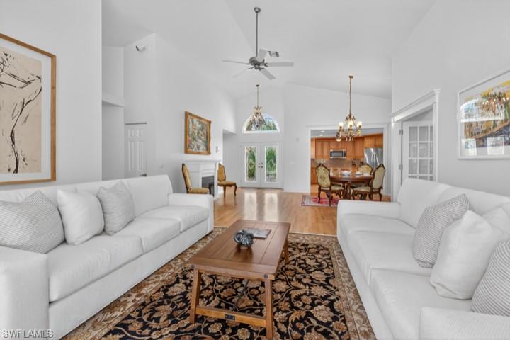43 Grey Wing Point Naples, FL 34113 - Photo 36 of 50 Living area featuring french doors, high vaulted ceiling, wood finished floors, ceiling fan, and a chandelier