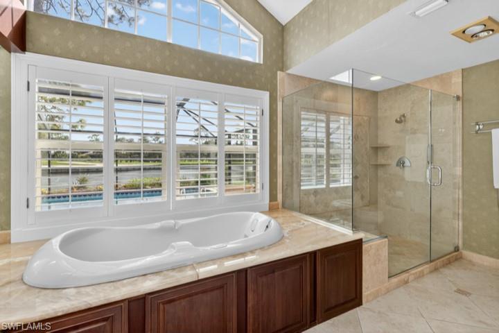 43 Grey Wing Point Naples, FL 34113 - Photo 41 of 50 Full bath with a bath, a shower stall, light tile patterned floors, wallpapered walls, and a water view