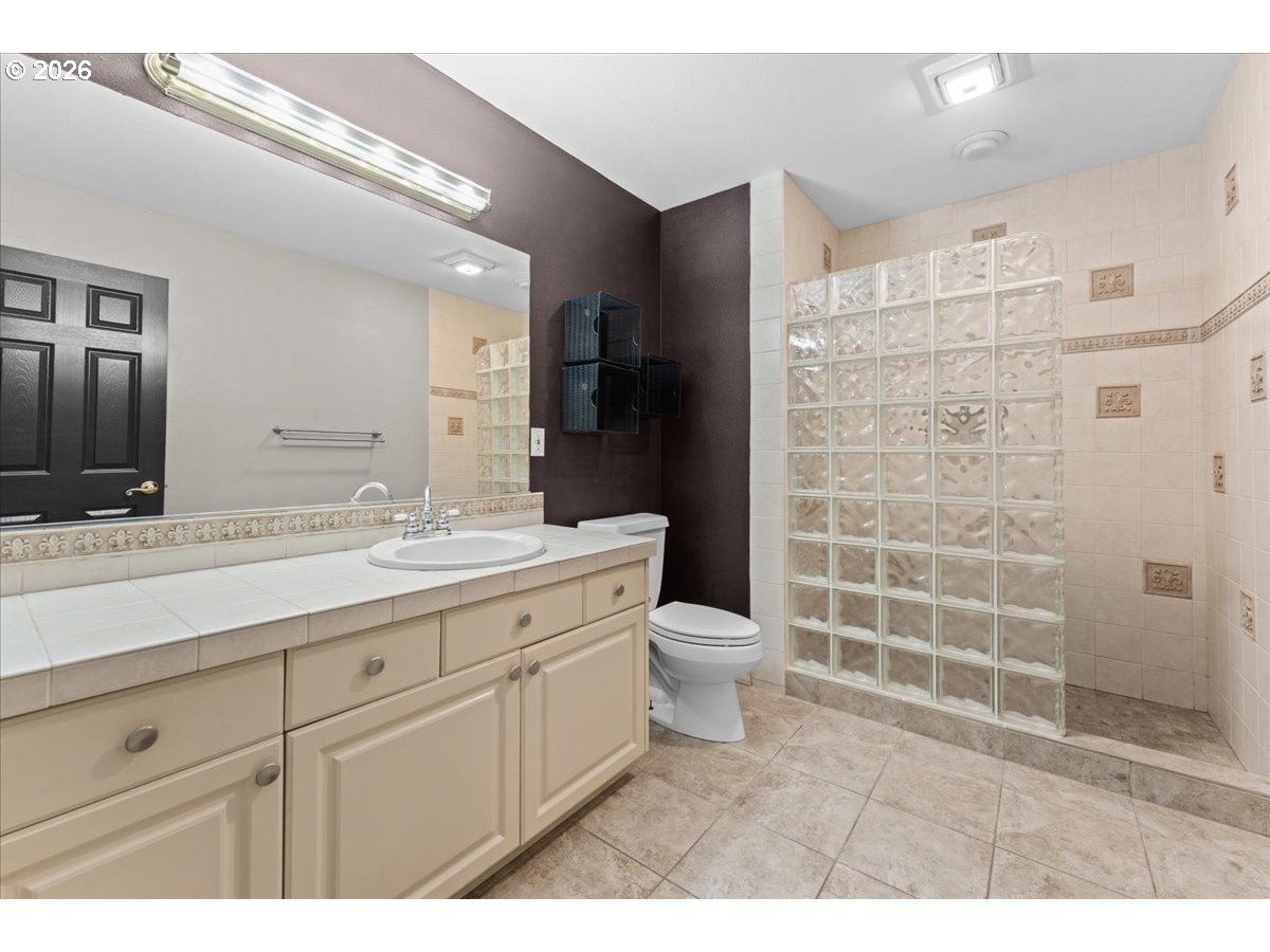 12431 Southwest 55th Place Portland, OR 97219 - Photo 31 of 40 a bathroom with a double vanity sink toilet and shower