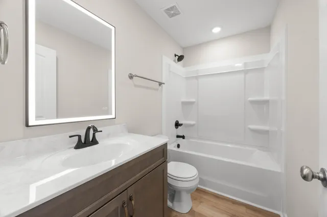 a bathroom with a sink a toilet a mirror and shower