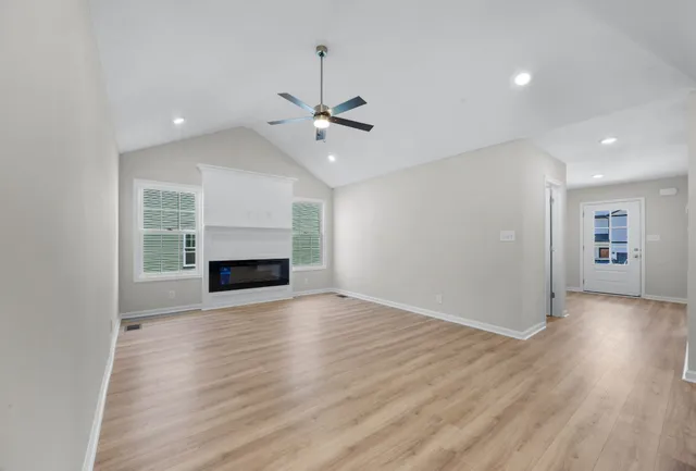 an empty room with wooden floor fireplace and windows