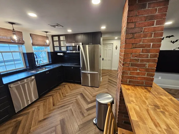 a kitchen with stainless steel appliances wooden floor and a refrigerator