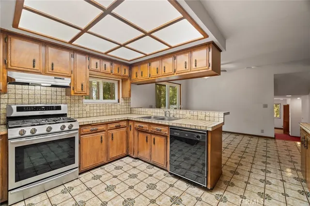 a view of an empty room with a window and a kitchen