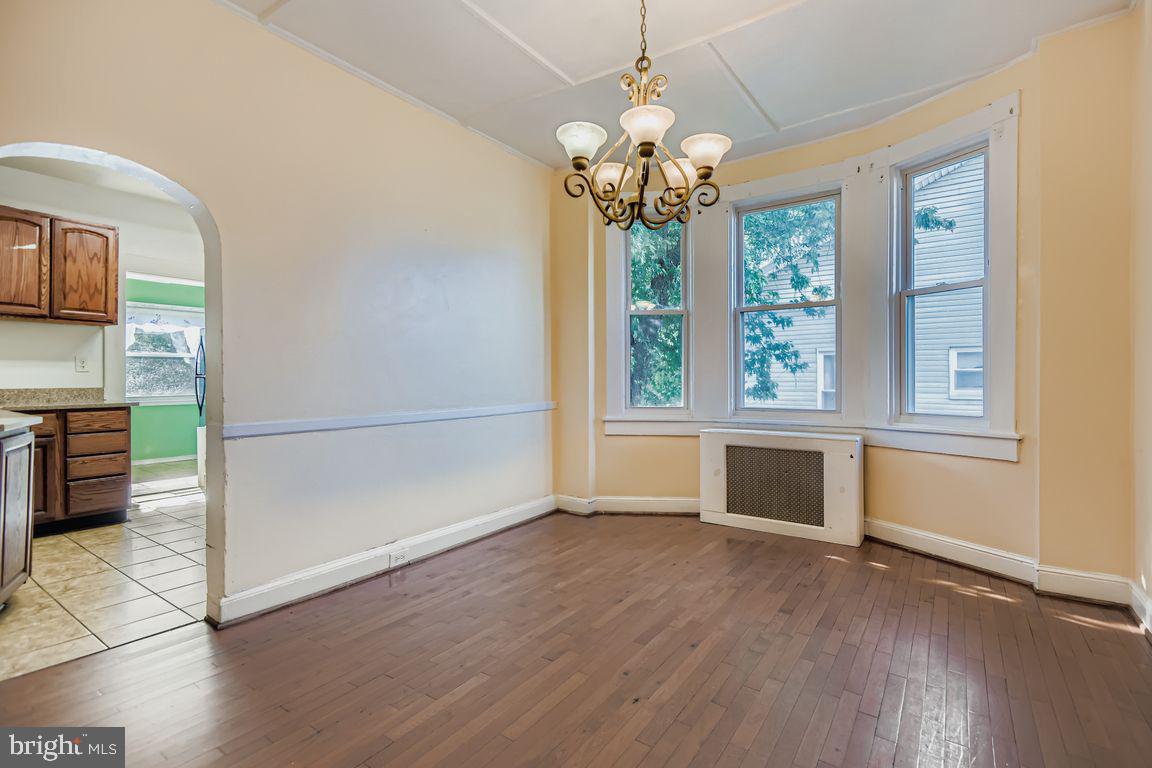 5710 Highgate Drive Baltimore, MD 21215 - Photo 7 of 28 an empty room with wooden floor chandelier and windows