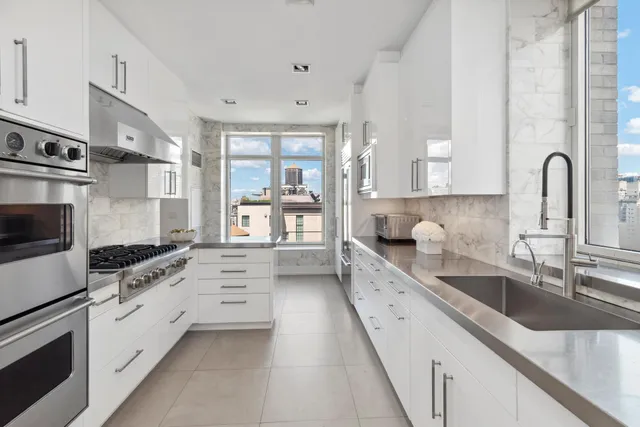 a large white kitchen with stainless steel appliances granite countertop a lot of counter space and a sink