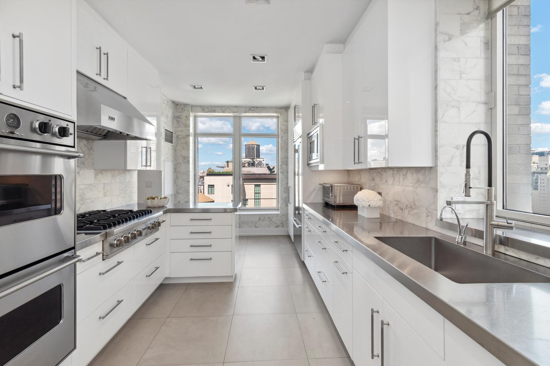515 Park Avenue, Unit 19 Manhattan, NY 10022 - Photo 7 of 19 a large white kitchen with stainless steel appliances granite countertop a lot of counter space and a sink