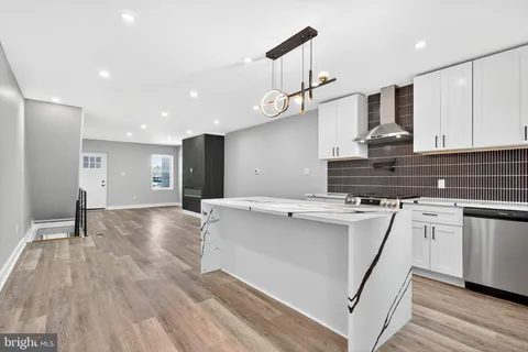 a view of kitchen with stainless steel appliances granite countertop a sink a stove a refrigerator and island with wooden floor