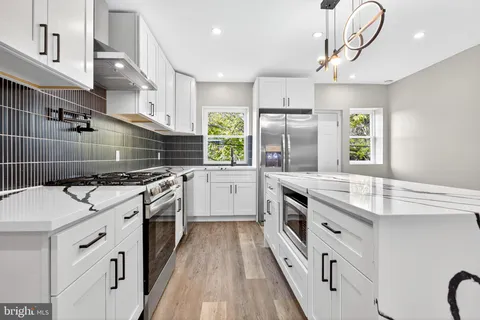 a kitchen with stainless steel appliances granite countertop a sink a stove and a refrigerator
