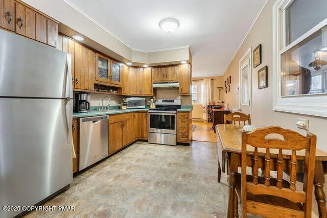 a kitchen with stainless steel appliances kitchen island granite countertop a refrigerator a stove a sink dishwasher a dining table and chairs with wooden floor