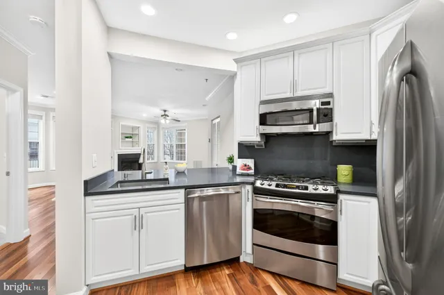 a kitchen with cabinets stainless steel appliances and wooden floor