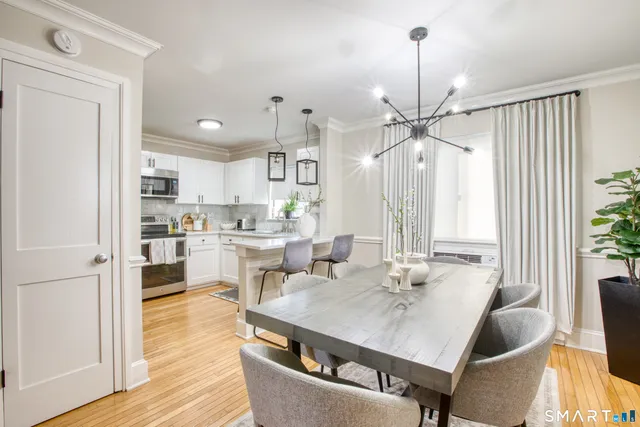 a living room with stainless steel appliances furniture a dining table and a chandelier