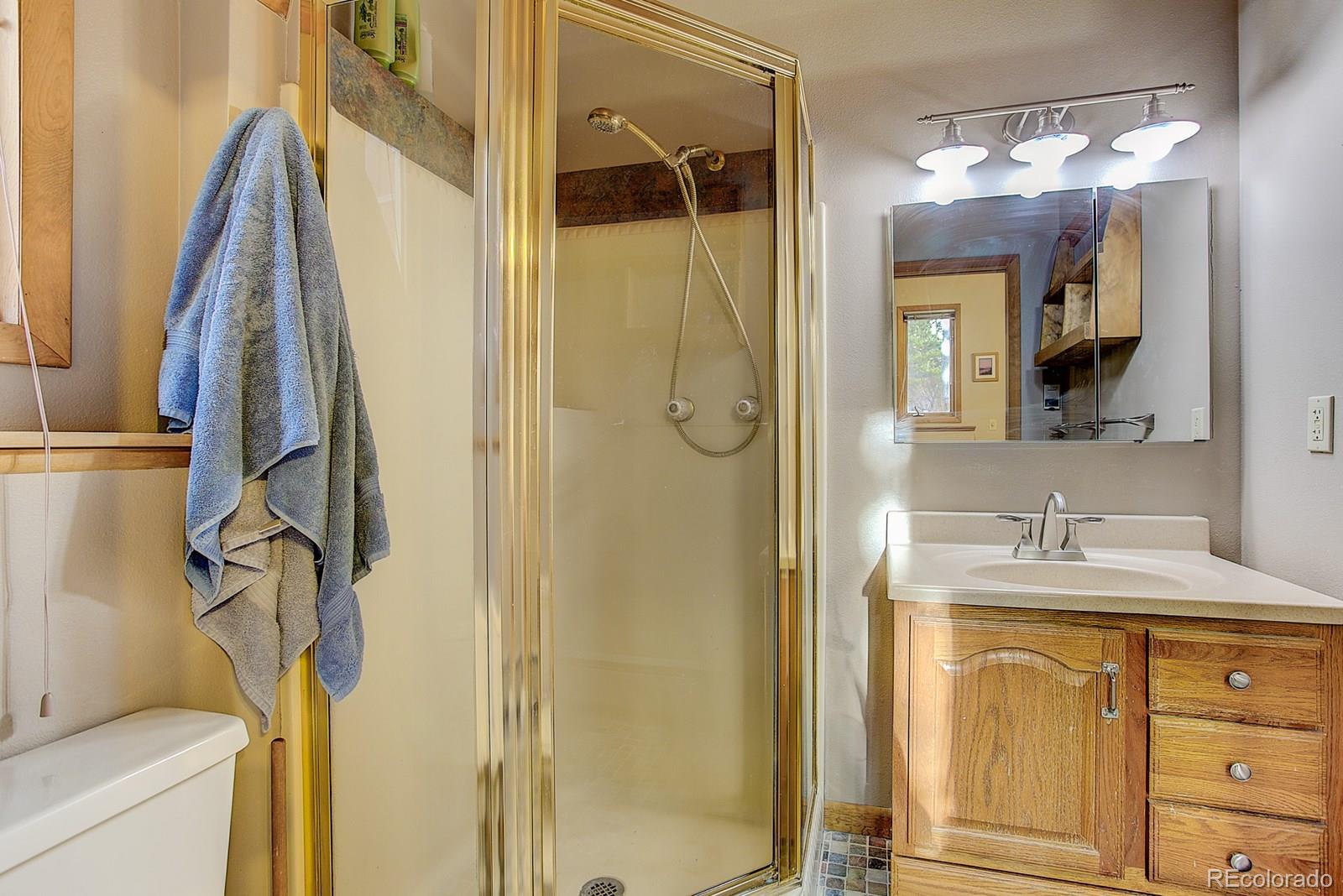 1983 Ridge Road Nederland, CO 80466 - Photo 20 of 30 a bathroom with a granite countertop sink a mirror a vanity and a shower
