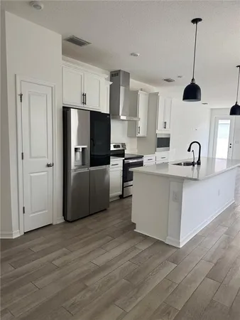 a kitchen with stainless steel appliances a sink a stove a refrigerator and island with wooden floor