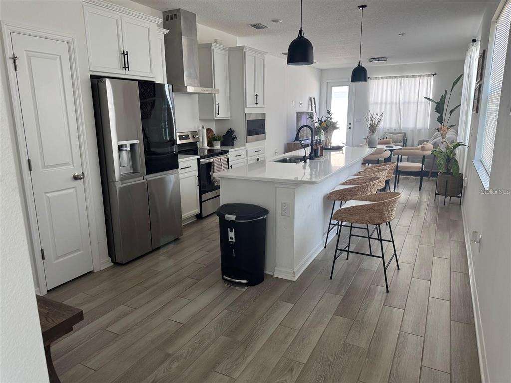 4356 Reisswood Loop Palmetto, FL 34221 - Photo 4 of 17 a kitchen with stainless steel appliances a refrigerator a sink dishwasher a stove and white cabinets with wooden floor