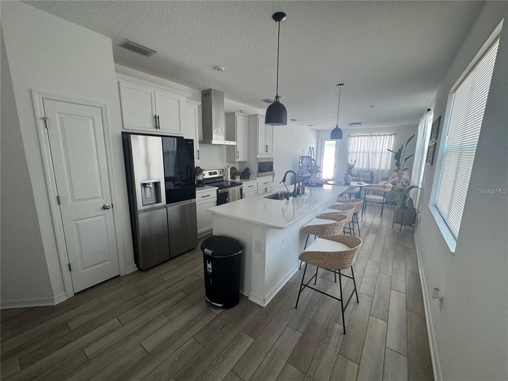 4356 Reisswood Loop Palmetto, FL 34221 - Photo 5 of 17 a kitchen with stainless steel appliances a refrigerator a sink dishwasher a stove and white cabinets with wooden floor