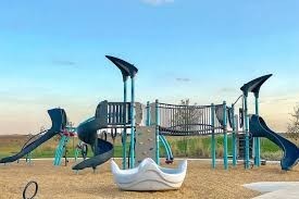 17439 Chester Valley Trail Hockley, TX 77447 - Photo 21 of 22 This photo shows a modern children's playground with slides, climbing structures, and swings set on a sandy surface. It's situated in an open area with clear skies, offering a family-friendly environment.