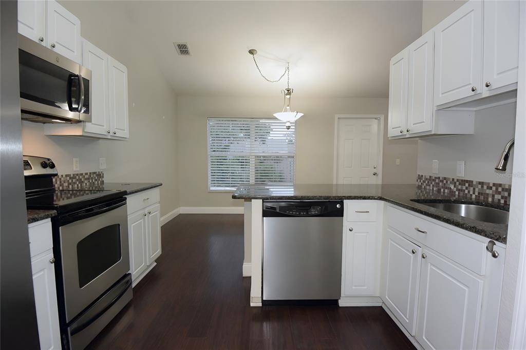 12042 Linden Drive Spring Hill, FL 34608 - Photo 16 of 41 a kitchen with kitchen island granite countertop a sink cabinets and stainless steel appliances