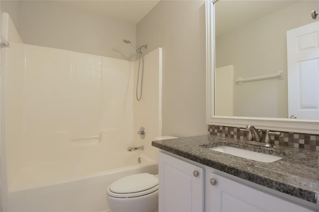 12042 Linden Drive Spring Hill, FL 34608 - Photo 30 of 41 a bathroom with a granite countertop sink a toilet and shower