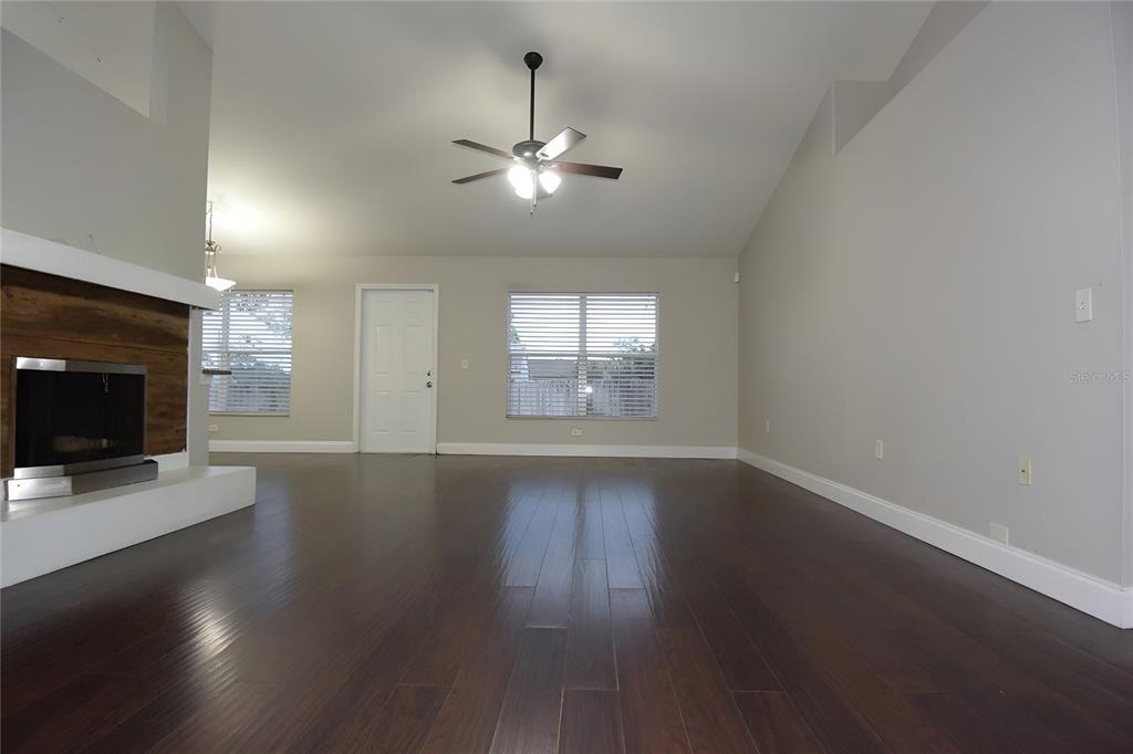 12042 Linden Drive Spring Hill, FL 34608 - Photo 9 of 41 an empty room with wooden floor fireplace and windows