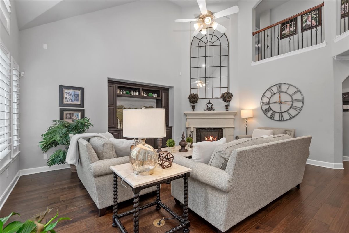 15519 Stallion Point Circle Cypress, TX 77429 - Photo 21 of 37 Living room featuring high vaulted ceilings, dark hardwood floors, a fireplace with a stone mantel, and a built-in dark wood cabinet