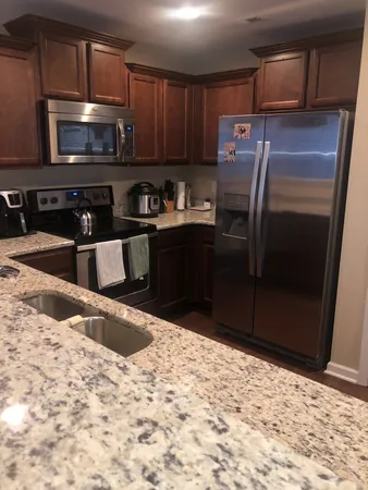 a kitchen with stainless steel appliances kitchen island granite countertop a refrigerator and a stove top oven