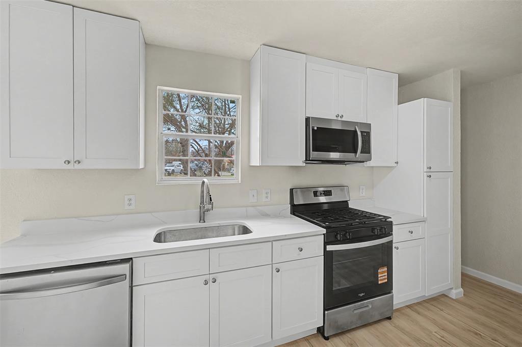 9021 White Settlement Road White Settlement, TX 76108 - Photo 9 of 33 a kitchen with stainless steel appliances a sink dishwasher stove and microwave with wooden floor