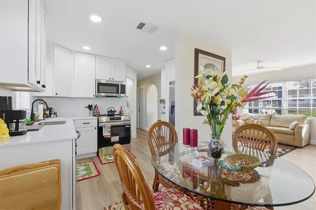 a kitchen with stainless steel appliances granite countertop a stove a sink a dining table and chairs
