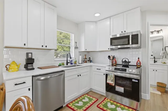 a kitchen with stainless steel appliances granite countertop a sink dishwasher a stove and a microwave oven with cabinets