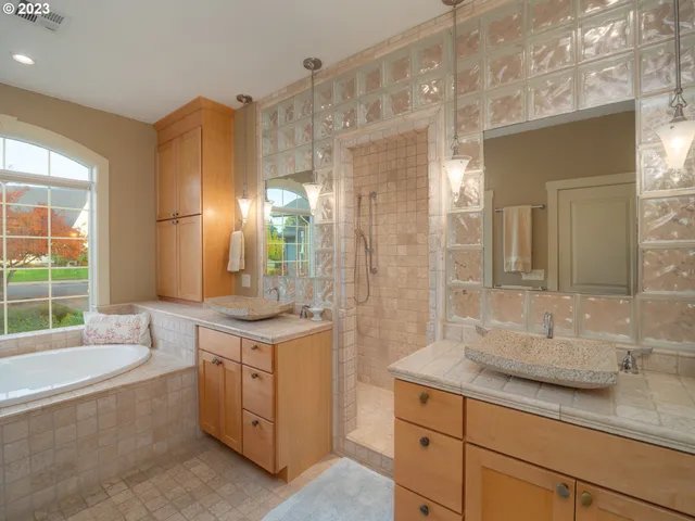 a bathroom with a granite countertop tub sink and mirror