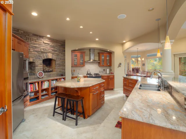 a large kitchen with stainless steel appliances granite countertop a lot of counter space and a sink