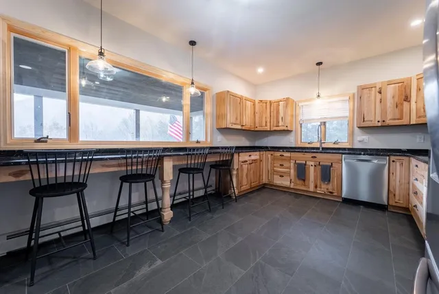 a kitchen with stainless steel appliances granite countertop a table chairs and a sink