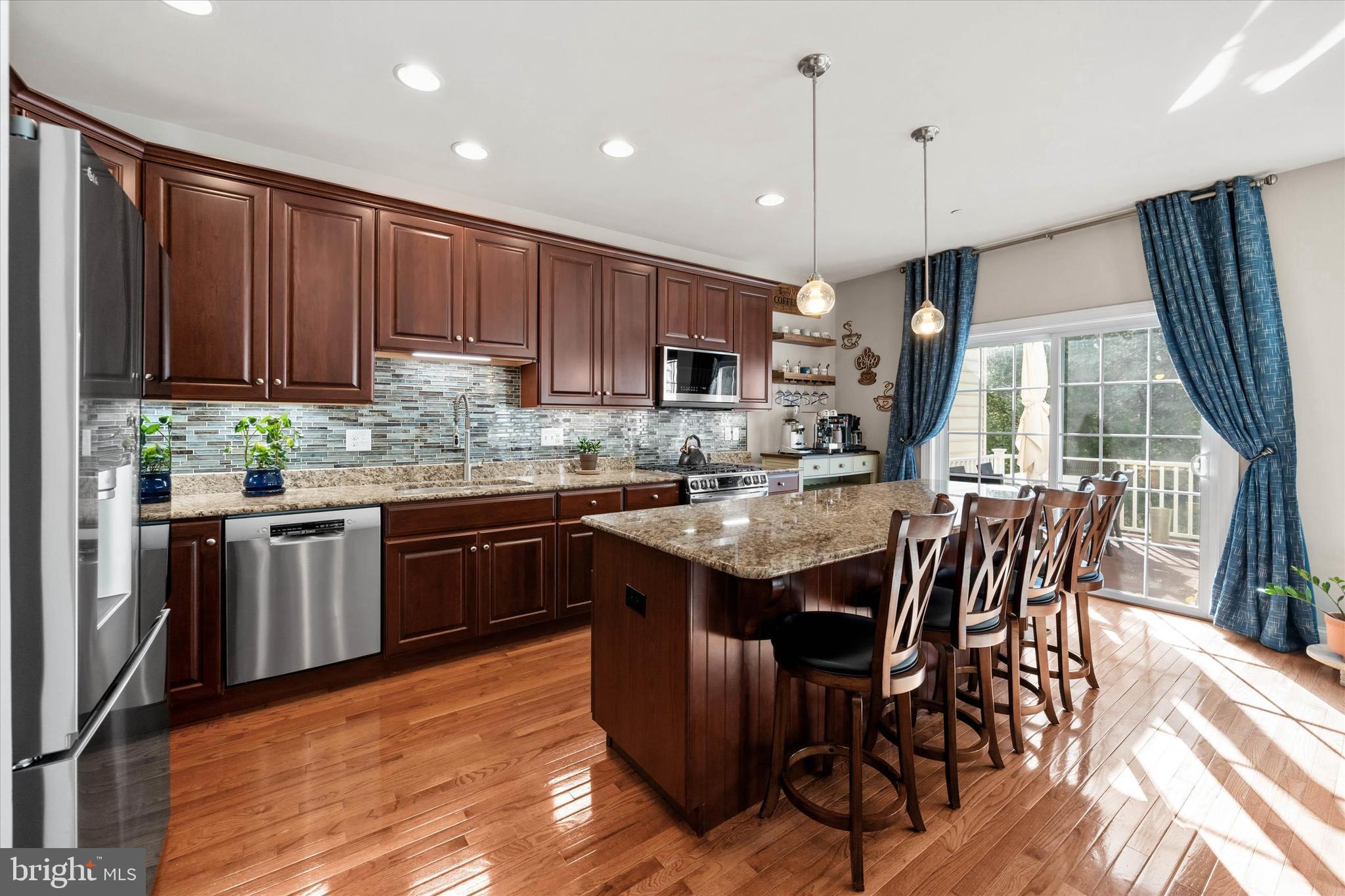 264 Deepdale Drive, Unit 31 Kennett Square, PA 19348 - Photo 7 of 34 a kitchen with stainless steel appliances granite countertop wooden floor a stove a sink a refrigerator with a dining table and chairs
