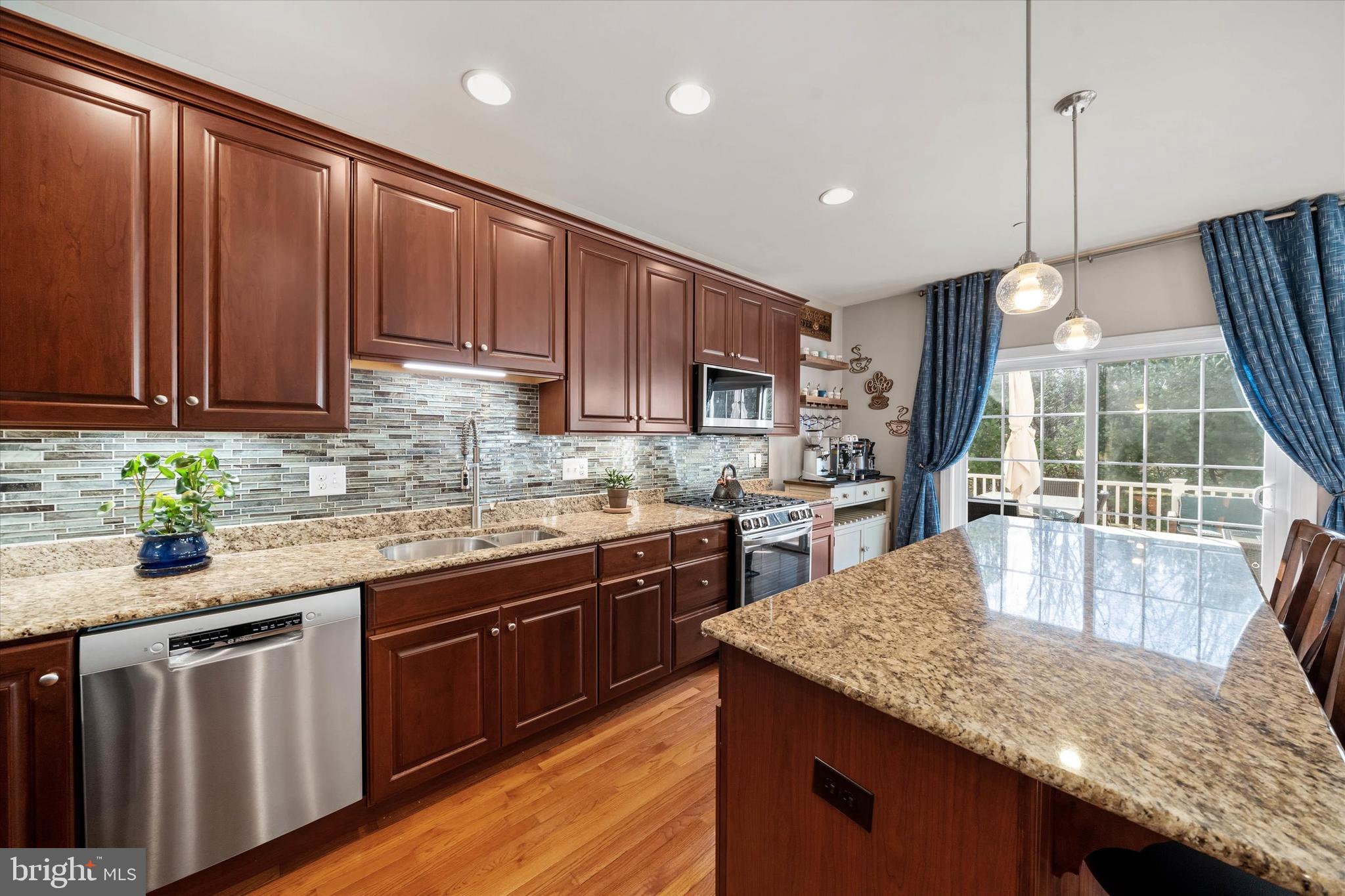 264 Deepdale Drive, Unit 31 Kennett Square, PA 19348 - Photo 9 of 34 a kitchen with kitchen island granite countertop wooden cabinets a stove a sink and a dishwasher with wooden floor