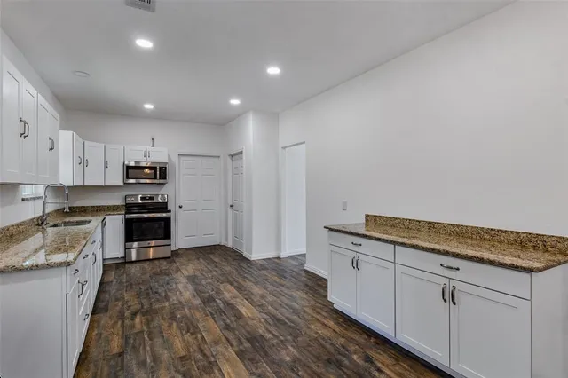 a kitchen with granite countertop white cabinets and stainless steel appliances