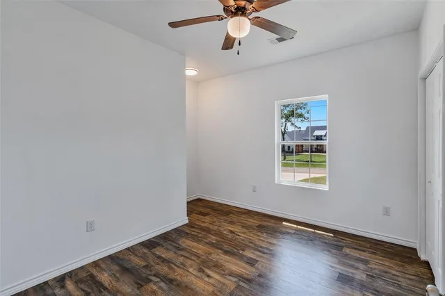 a view of an empty room with a window and wooden floor