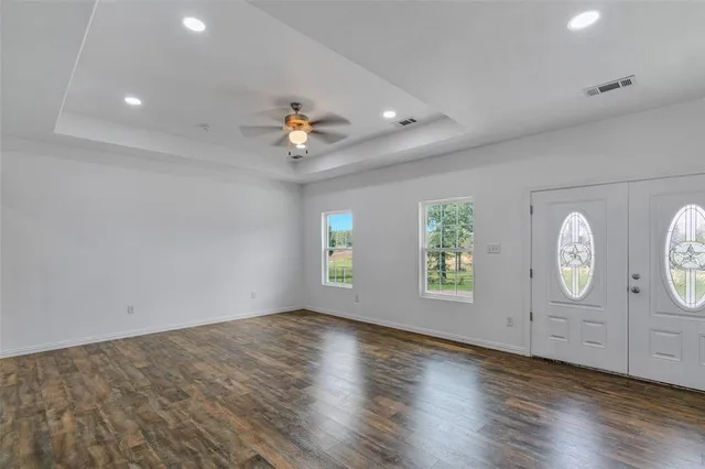 an empty room with wooden floor and windows