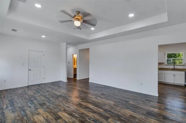a view of an empty room with wooden floor and a ceiling fan