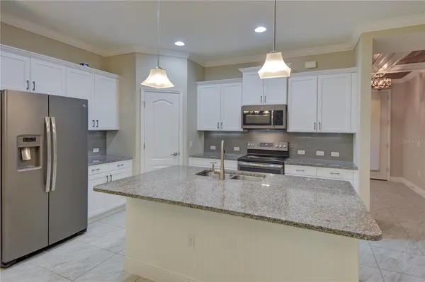 a kitchen with kitchen island a counter space a sink appliances and cabinets