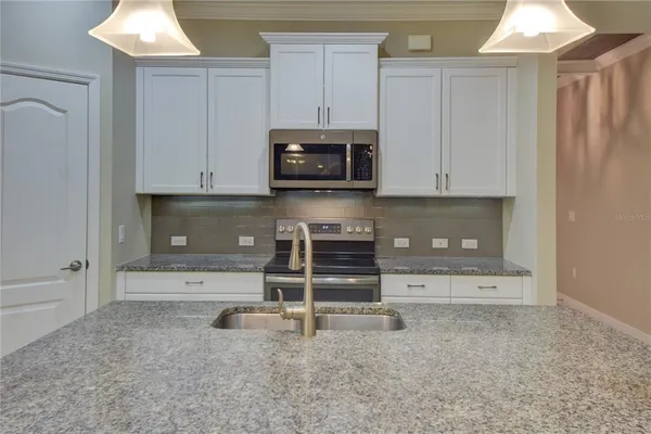 a kitchen with granite countertop white cabinets and stainless steel appliances