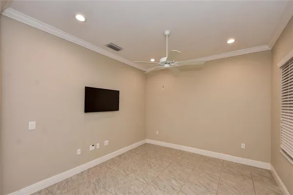 an empty room with a flat screen tv and chandelier fan