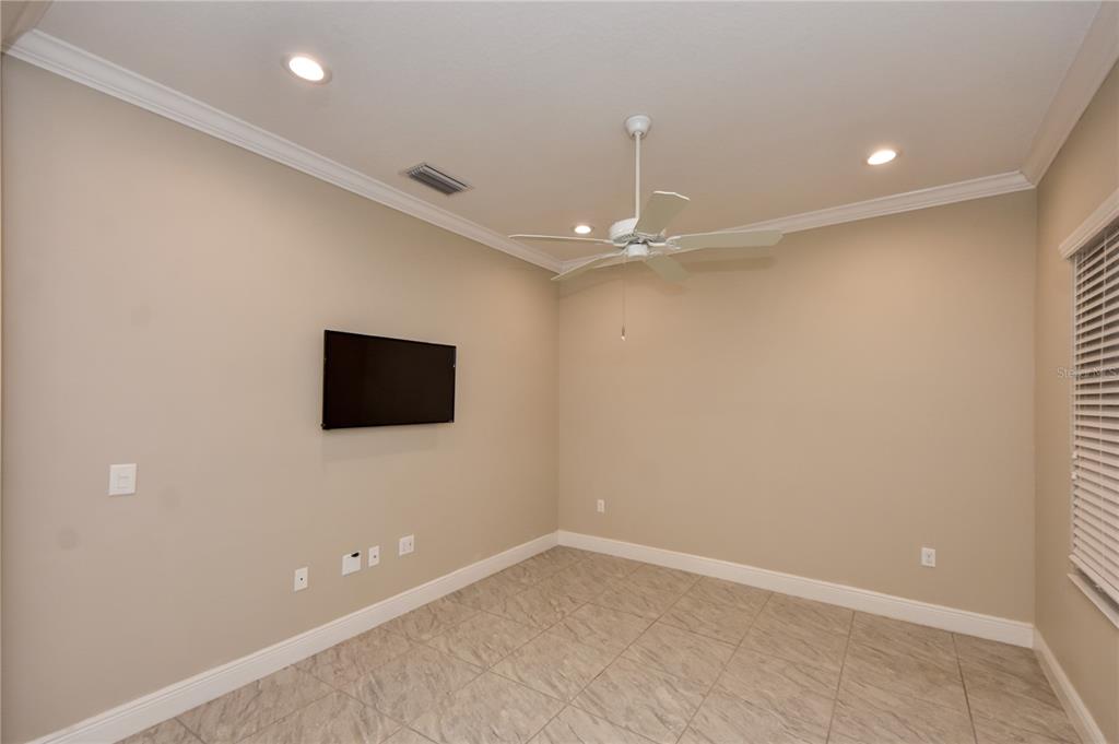 7408 Ridgelake Circle Bradenton, FL 34203 - Photo 7 of 39 an empty room with a flat screen tv and chandelier fan