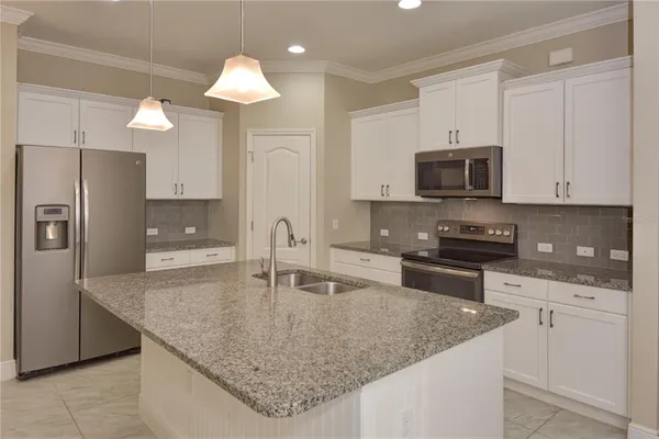 a kitchen with granite countertop a sink a counter top space appliances and cabinets