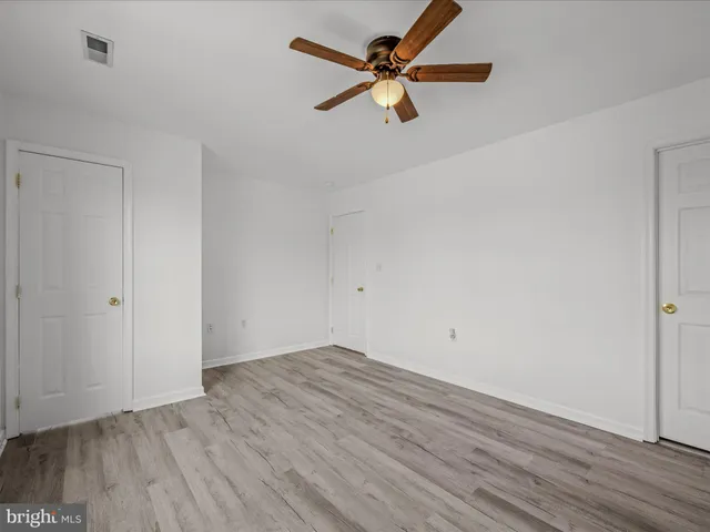 an empty room with wooden floor fan and windows
