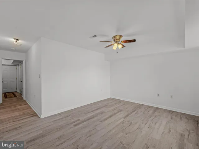 a view of a room with wooden floor and a ceiling fan