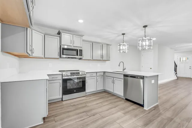 a kitchen with stainless steel appliances granite countertop a stove top oven a sink dishwasher and a microwave oven with cabinets