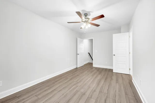 an empty room with wooden floor fan and windows