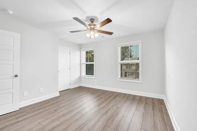 a view of an empty room with wooden floor and a window