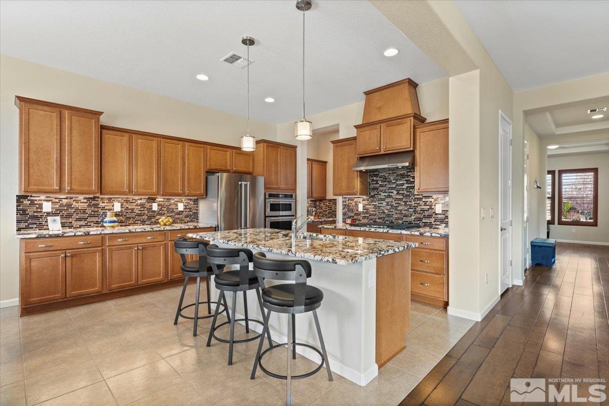 2300 Arpagos Lane Reno, NV 89521 - Photo 10 of 40 a kitchen with stainless steel appliances granite countertop a stove top oven a refrigerator a sink and white cabinets